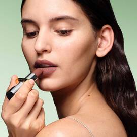 Model wearing Prada Monochrome Hyper Matte Lipstick in shade B13, showcasing the rich color payoff.