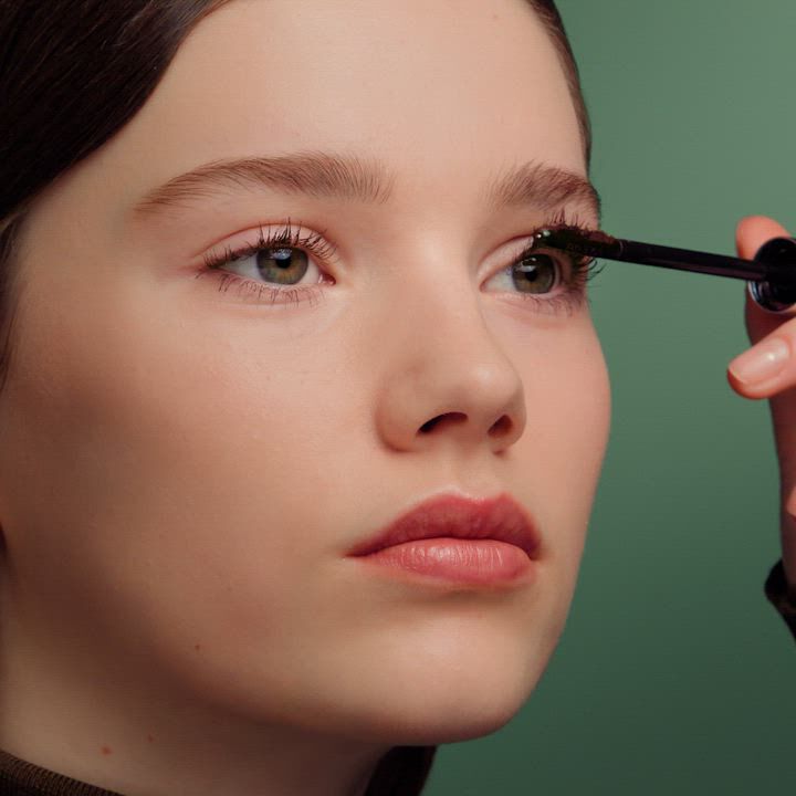 Model showing the texture and finish of the Prada Reflection Glossy Liquid Balm. Overlaid texts read: "Infused with Hyaluronic Acid" and "Up to 24H Hydration".