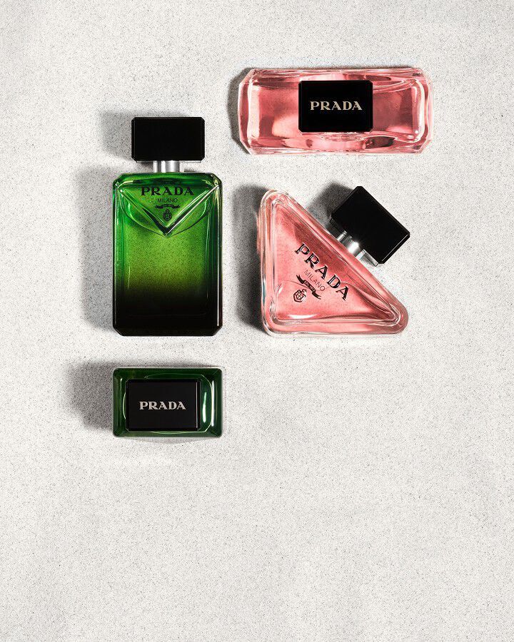 Prada Paradoxe Eau De Parfum and Paradigme Eau De Parfum facing view and above view on white sand 