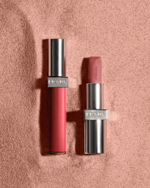 Prada Reflection Lip Gloss and Monochrome Lipstick on muted reddish sand