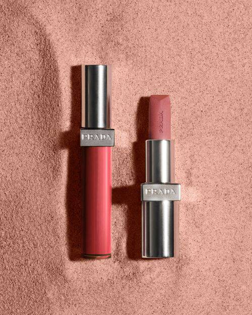 Prada Reflection Lip Gloss and Monochrome Lipstick on muted reddish sand