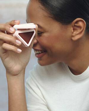 Prada Summer Stories Medium Skin Model with Prada Touch Blush in hand on a muted beach background