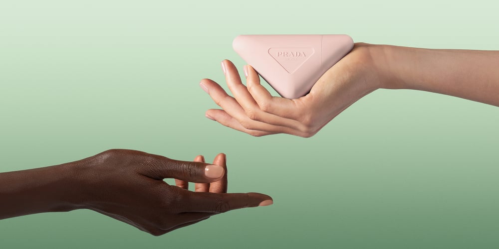 Prada Paradoxe Hand Cream Key Visual with dark and light skin hands on a Green Background